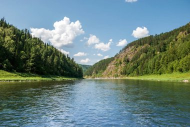 Sibirya 'nın manzarası. Kiya Nehri, dağ kıyıları ve Kemerovo bölgesindeki yeşil ormanlar. Mavi gökyüzü ve bulutlu gündüz manzarası.