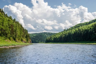 Sibirya 'nın manzarası. Kiya Nehri, dağ kıyıları ve Kemerovo bölgesindeki yeşil ormanlar. Mavi gökyüzü ve bulutlu gündüz manzarası.