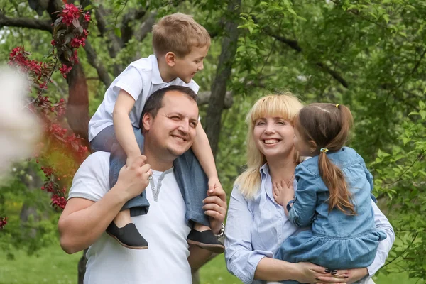 Gelukkig gezin met twee kinderen in lentetuin — Stockfoto