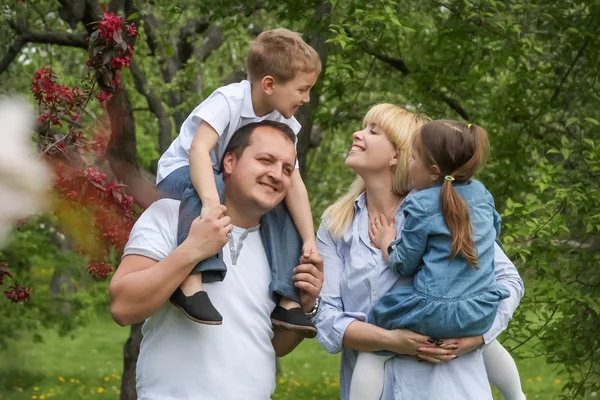 Счастливая семья с двумя детьми, развлекающимися в саду — стоковое фото