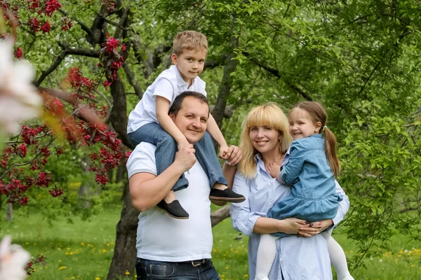 Счастливая семья с двумя детьми в саду — стоковое фото