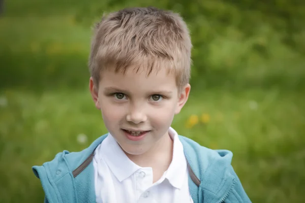Sex år gammal pojke porträtt över green — Stockfoto