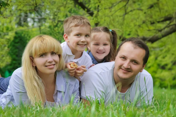 Gelukkig gezin met twee kinderen liggen op gras — Stockfoto