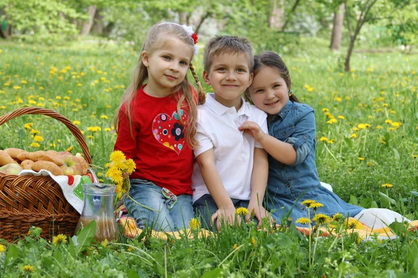 Kids having picnic among dandelion field — Stock Photo, Image