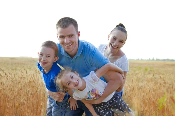 Gezin met twee kinderen plezier onder tarweveld — Stockfoto
