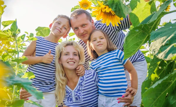 Lycklig familj med två barn i solrosor — Stockfoto