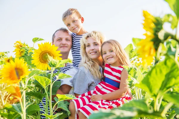 Щаслива сім'я з двома дітьми в соняшниках — стокове фото
