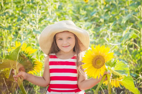 Lächelndes Mädchen mit Hut zwischen Sonnenblumen — Stockfoto