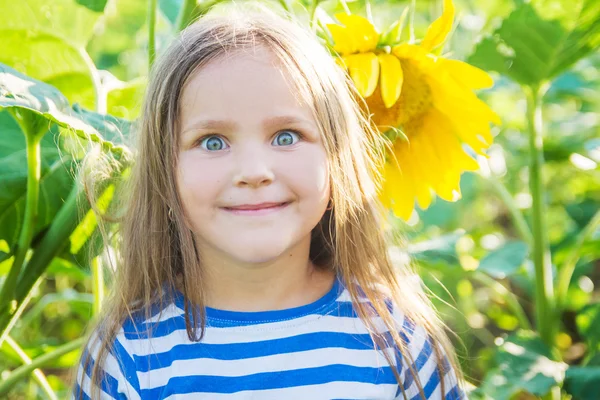 Mädchen mit lustigem Gesicht inmitten von Sonnenblumen — Stockfoto