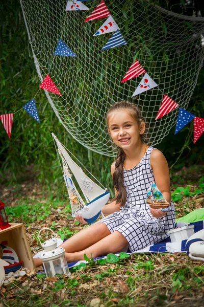 Niña sosteniendo dos pequeños barcos entre la decoración marina —  Fotos de Stock