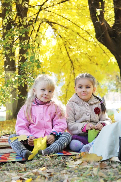 Szczęśliwy dziewcząt gra pod autumn odchodzi — Zdjęcie stockowe