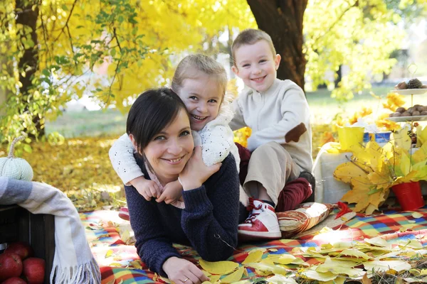 Szczęśliwe dzieci przytulanie ich matki pod autumn drzewa — Zdjęcie stockowe