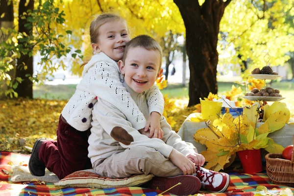 Sister and brother hugging under autumn tree — Stock Photo, Image