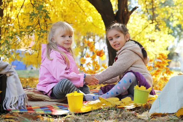 Chicas felices jugando bajo las hojas de otoño —  Fotos de Stock