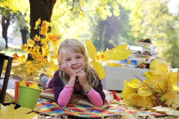 Fille couchée avec des feuilles d'automne sous les arbres — Photo