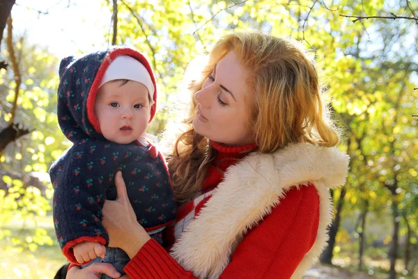 Mamma och baby flicka talar i höst park — Stockfoto