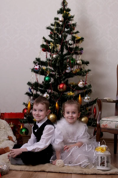 Meisje en jongen onder kerstboom — Stockfoto