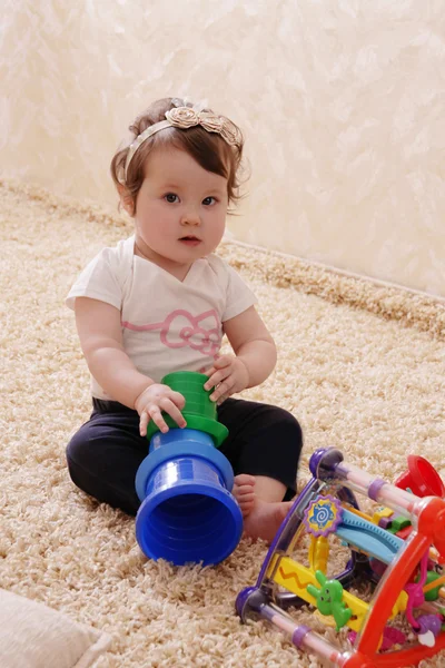 Tien maanden babymeisje spelen met piramide Stockfoto