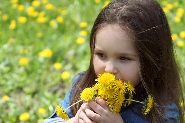 Girl smelling dandelions — Stock Photo, Image