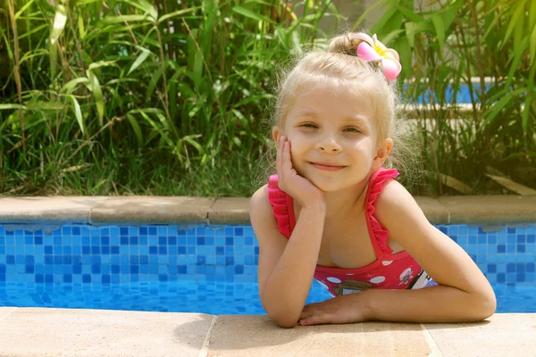 Menina na piscina com uma mão perto da bochecha — Fotografia de Stock
