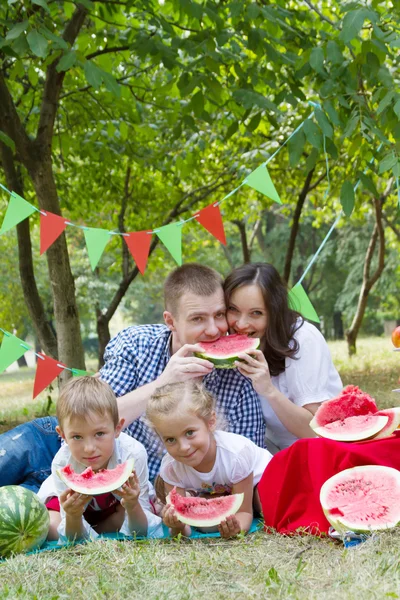 Familia con niños comiendo sandías Imágenes de stock libres de derechos