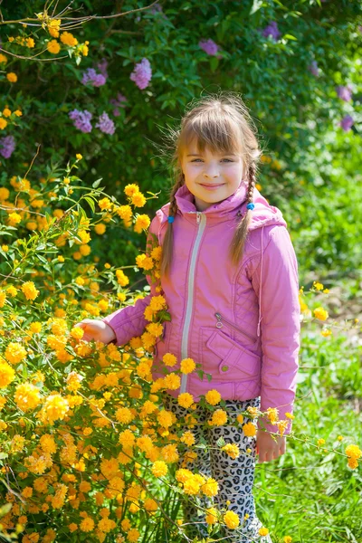 Söt tjej på en bakgrund av gröna och gula blommor på våren — Stockfoto