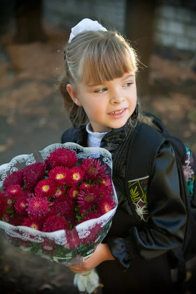 Schoolgirl with a bouquet of flowers in front of school — Stock Photo, Image