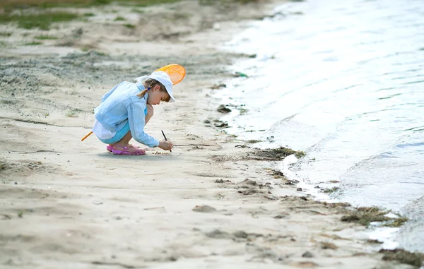 Chica en una gorra en la playa con una red dibuja en la playa —  Fotos de Stock