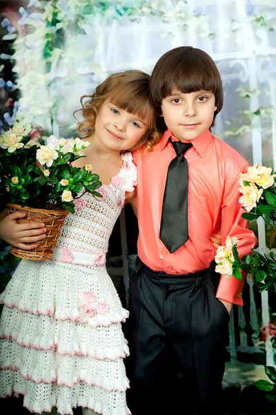 Smart Mädchen und Junge mit Blumen in eleganten Kleidern — Stockfoto