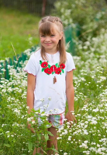 Veselá dívka v ukrajinských výšivky na květinové pozadí — Stock fotografie