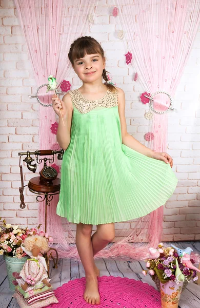 Мила дівчина в зеленій плісированій сукні стоїть з пташкою в його хані — стокове фото