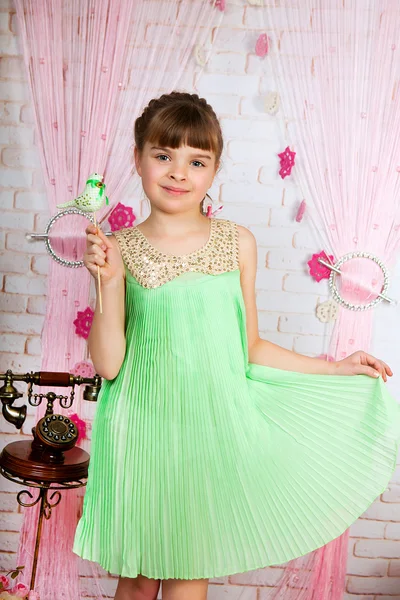 Carino ragazza in un abito verde con un ptichkoyv pieghettato mani nel — Foto Stock