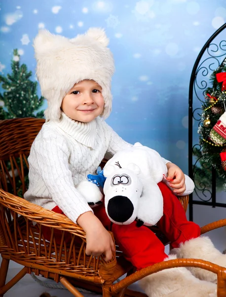 Cutest boy in a white fur hat with a bear on New Year's backgrou — Stock Photo, Image