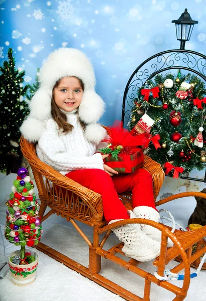 Beautiful girl in a white cap and knit sweater sitting in wicker — Stock Photo, Image