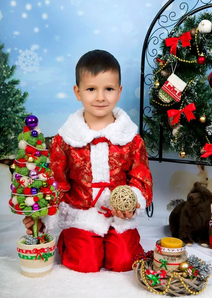 Belo menino em um terno vermelho nas decorações de Ano Novo um — Fotografia de Stock