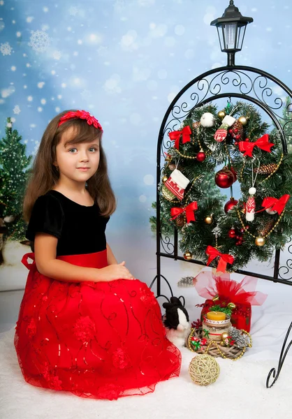 Hermosa chica en un vestido rojo y negro sentado en el fondo — Foto de Stock