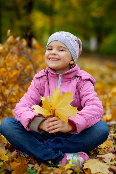 Bella bambina in giacca rosa e cappello con foglie gialle — Foto Stock