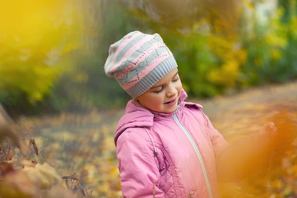 Hermosa niña en una chaqueta rosa y sombrero en el backgro de otoño —  Fotos de Stock