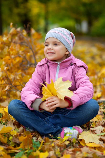 Mooi meisje in een roze jas en muts met gele verlof — Stockfoto