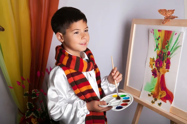 Ένα μικρό αγόρι στο ριγέ κασκόλ μια ζωγραφική μια εικόνα σε ένα καβαλέτο — Φωτογραφία Αρχείου