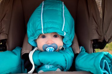 Güzel genç kadın anne bebeğiyle bebek arabasında yürüyor..