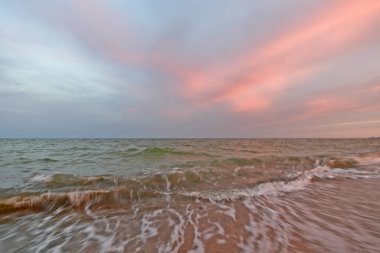 Azov Denizi sahilinde güzel bir akşam gün batımı. Gökyüzünün ve denizin renkli renkleri.