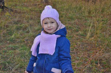 Çocuk ve anne, sonbaharda ormanda ateşin yanında ısınırlar..