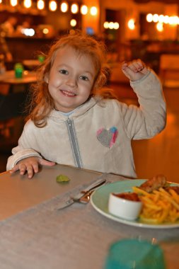 Çocuk kız restoranda yemek yiyor..