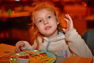 Çocuk kız restoranda yemek yiyor..