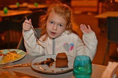 Çocuk kız restoranda yemek yiyor..