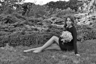 14 yaşında güzel bir genç kız, bir dinlenme merkezinde, doğal manzaraların arka planına karşı poz veriyor, elinde bir buket çiçekle..