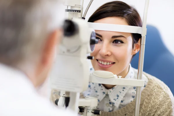 Kijken van de vrouw in de oftalmoscoop — Stockfoto