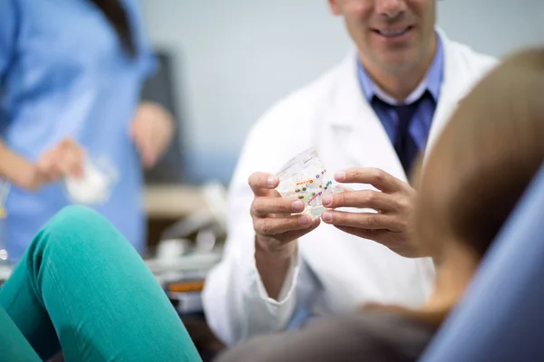Стоматолог держит брекеты на кронштейне — стоковое фото