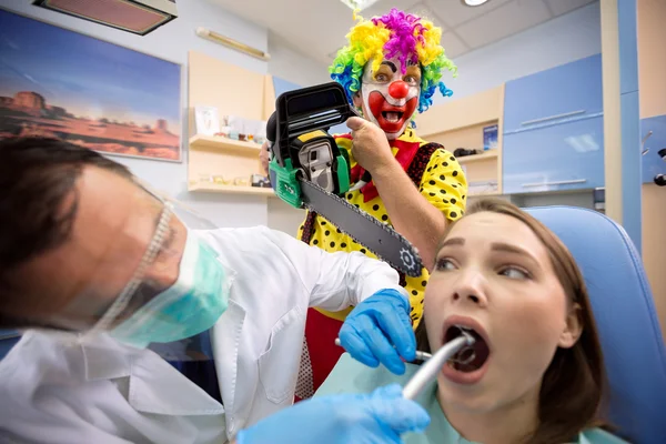 Menina em tratamento dentário com palhaço louco atrás — Fotografia de Stock